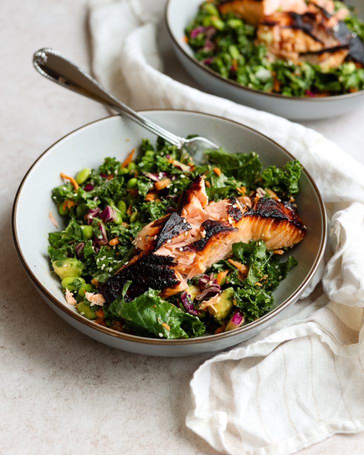 salmon kale salad in a bowl with a silver fork