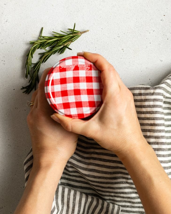 hands holding a white and red checked jar