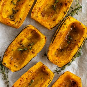 six roasted delicata squash halves on a platter lined with parchment paper