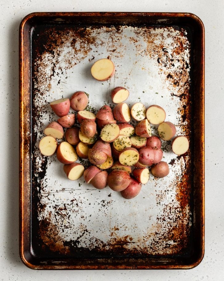 baby red potatoes cut in half on a baking sheet with seasonings