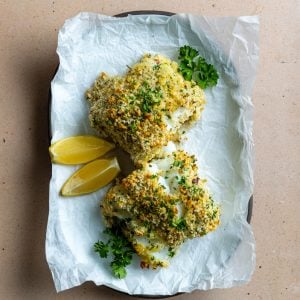 two pieces of crispy baked cod on a plate with parchment paper