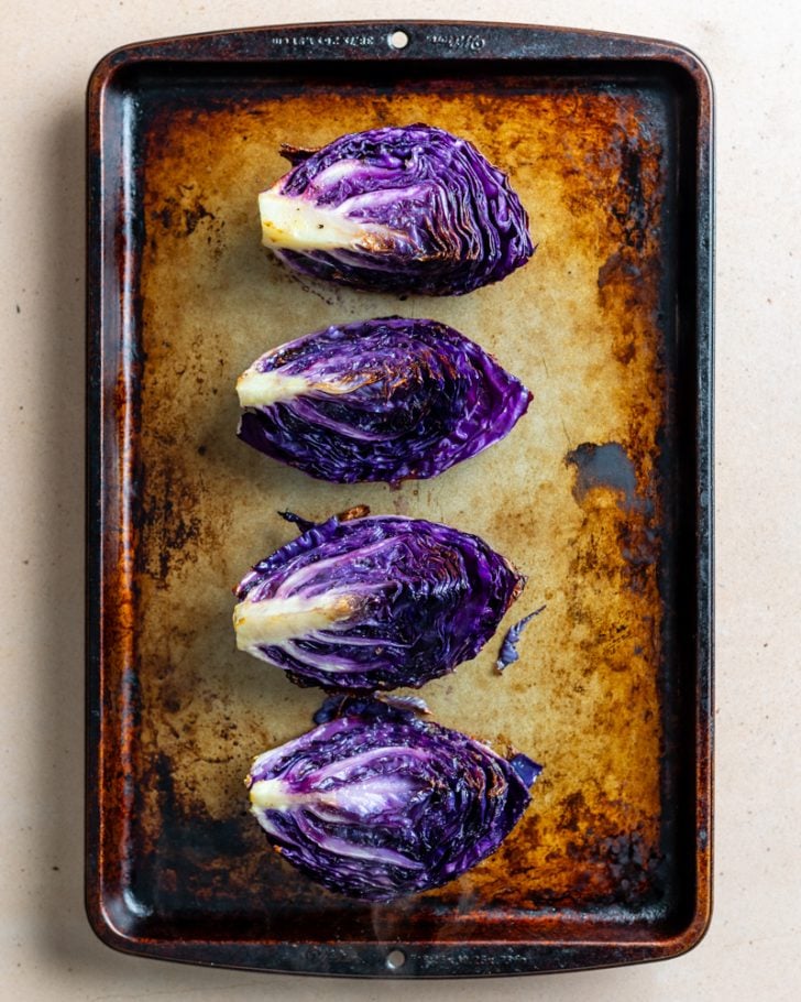 4 purple cabbage wedges on a baking sheet
