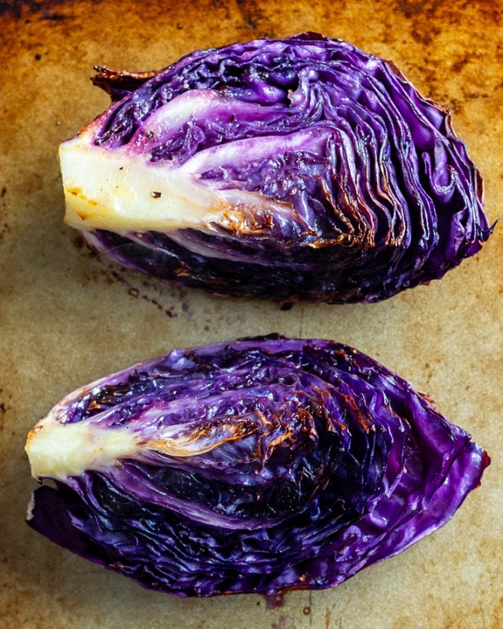 two roasted red cabbage wedges on a baking sheet