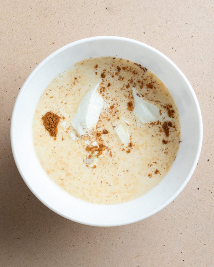 Greek yogurt, milk, and cinnamon in a white bowl